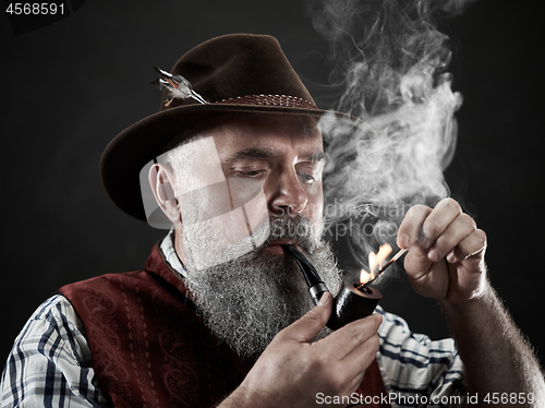 Image of dramatic portrait of senior smoking tobacco pipe