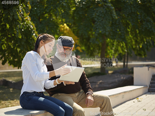 Image of Portrait of young girl sitting with grandfather at park