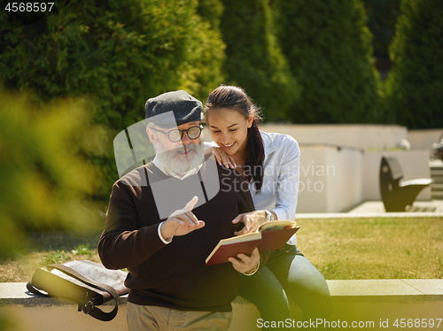 Image of Portrait of young girl embracing grandfather at park