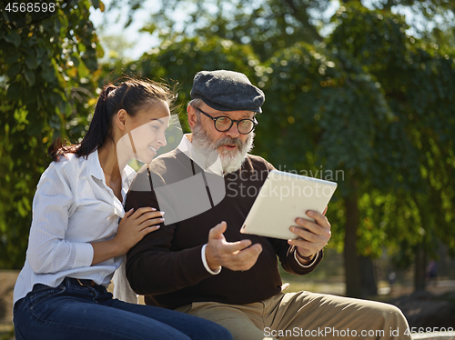 Image of Portrait of young girl sitting with grandfather at park