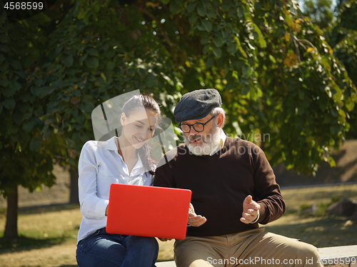 Image of Portrait of young girl sitting with grandfather at park