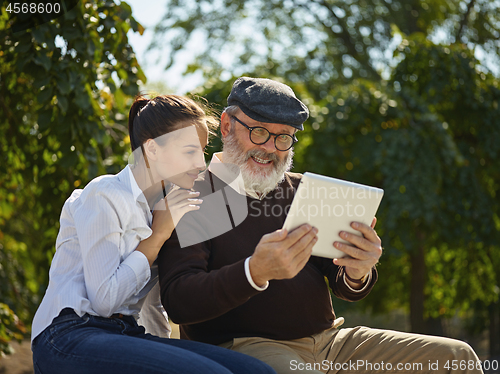 Image of Portrait of young girl sitting with grandfather at park