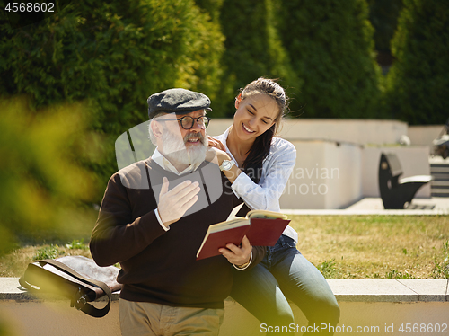 Image of Portrait of young girl embracing grandfather at park