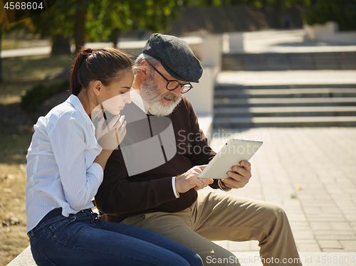 Image of Portrait of young girl sitting with grandfather at park