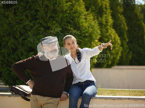 Image of Portrait of young girl embracing grandfather at park