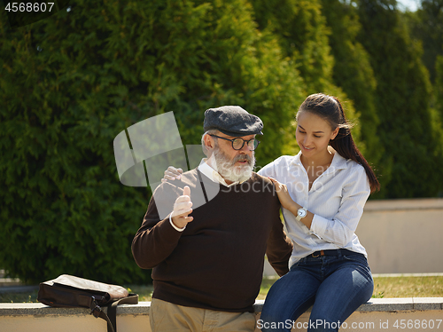 Image of Portrait of young girl embracing grandfather at park