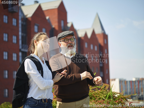 Image of Portrait of young girl embracing grandfather at park