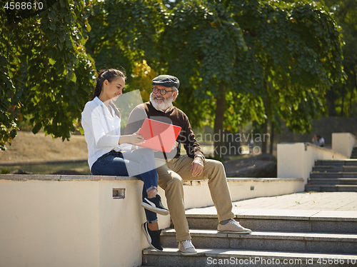 Image of Portrait of young girl sitting with grandfather at park