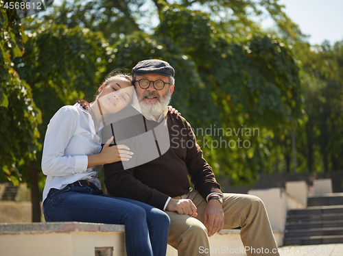 Image of Portrait of young girl embracing grandfather at park