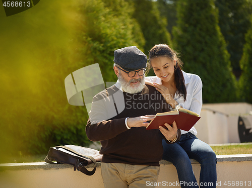 Image of Portrait of young girl embracing grandfather at park