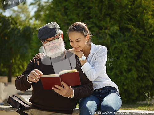 Image of Portrait of young girl embracing grandfather at park