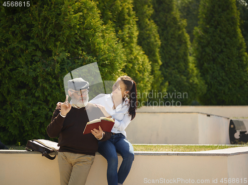 Image of Portrait of young girl embracing grandfather at park