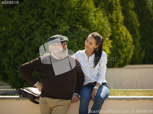 Image of Portrait of young girl embracing grandfather at park