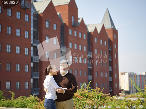 Image of Portrait of young girl embracing grandfather at park