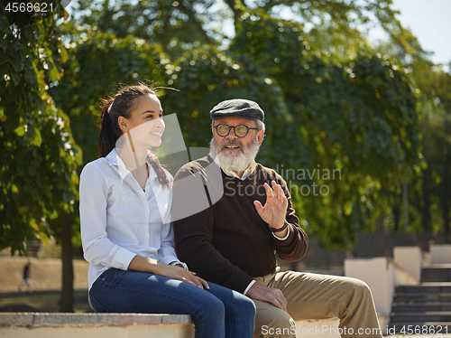 Image of Portrait of young girl embracing grandfather at park