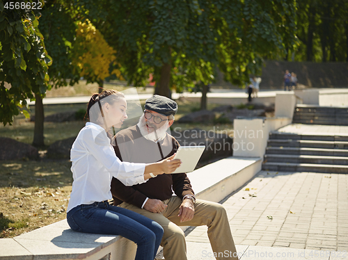 Image of Portrait of young girl sitting with grandfather at park