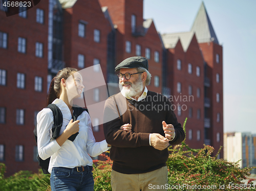 Image of Portrait of young girl embracing grandfather at park