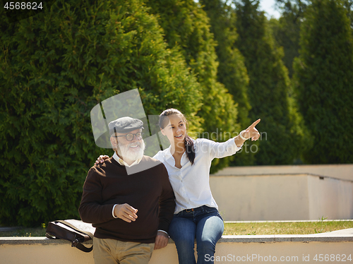 Image of Portrait of young girl embracing grandfather at park