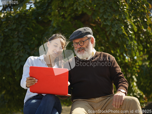 Image of Portrait of young girl sitting with grandfather at park