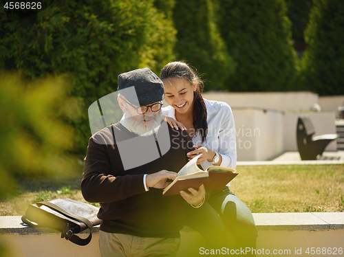 Image of Portrait of young girl embracing grandfather at park