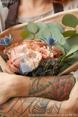 Image of Close up of fresh tender roses and eryngium in a woman\'s hands with tattoo. Congratulation concept of Mother\'s Day.