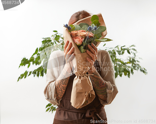 Image of A fresh gently roses as a bouquet in a female hands on a white background with green leaf, copy space. Post card for Mother\'s Day.