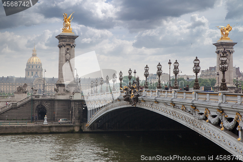Image of Pont Alexandre III bridge overlooking the city and the river, cloudy day. France Paris