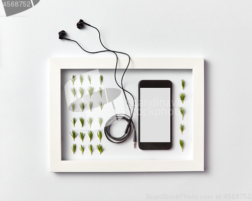 Image of Frame with organic pine needles pattern, smartphone mock-up and headphones on a light background.