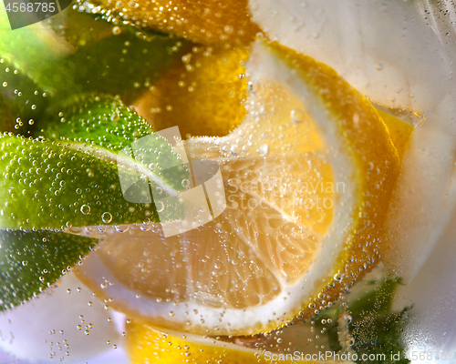 Image of Macro photo of fresh lime and lemon slices with bubbles in the glass. Summer cold drink