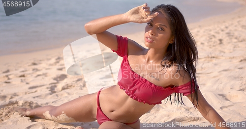 Image of Sensual brunette in wet swimsuit lying on sand