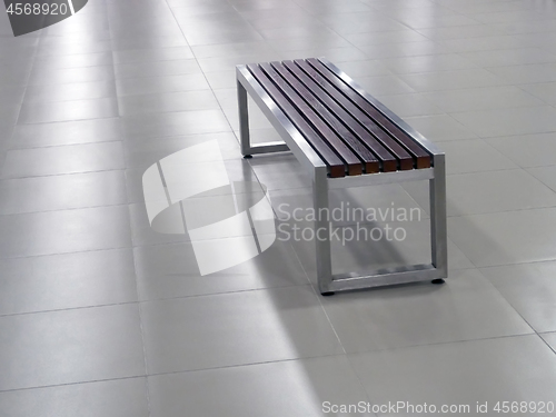 Image of Bench with steel frame and wooden seat elements on the tile floor