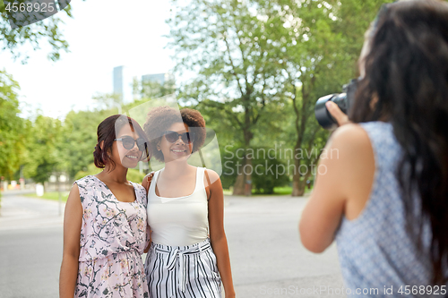 Image of woman photographing her friends in summer park