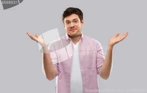 Image of young man shrugging over grey background