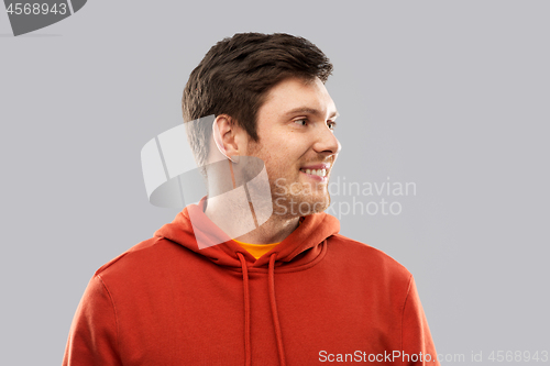 Image of smiling young man in red hoodie over grey