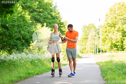 Image of couple with roller skates riding in summer park