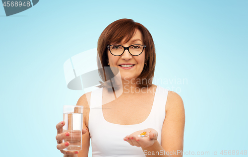 Image of senior woman with glass of water and pills