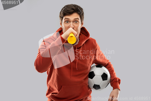 Image of football fan with soccer ball blowing horn