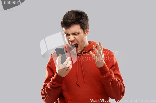 Image of mad man in red hoodie screaming to smartphone