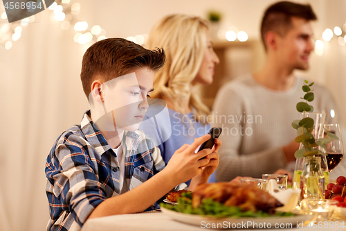 Image of boy with smartphone at family dinner party