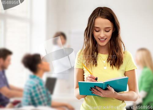 Image of teenage student girl writing to notebook at school