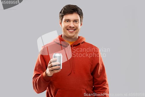 Image of happy young man drinking soda from tin can