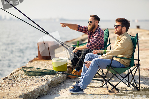 Image of happy friends with fishing rods on pier