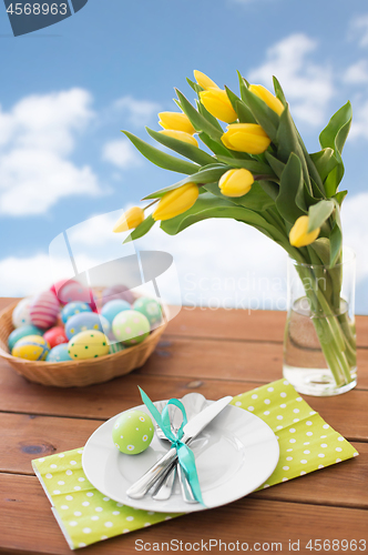 Image of easter eggs in basket, plates, cutlery and flowers