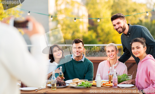 Image of happy friends photographing at rooftop party