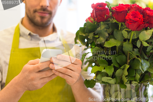 Image of florist with smartphone and roses at flower shop