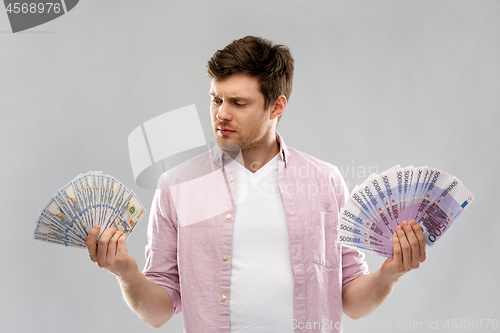 Image of uncertainy man with fans of euro and dollar money