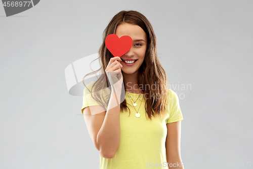 Image of smiling teenage girl covering her eye by red heart