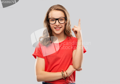 Image of smiling student girl in glasses pointing finger up