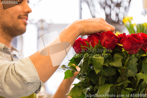 Image of florist or seller setting red roses at flower shop