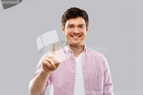 Image of young man showing one finger over grey background